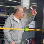 Kev Johns MBE raises a pair of scissors to cut a yellow ribbon at the entrance to the new CK Foodstores in Bynea.