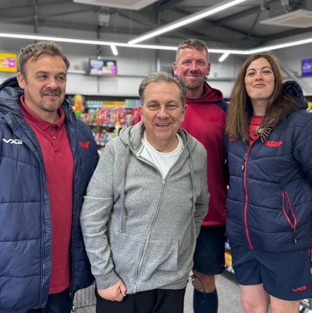Kev Johns MBE standing with three members of staff wearing CK Foodstores branded jackets inside the new Bynea store.