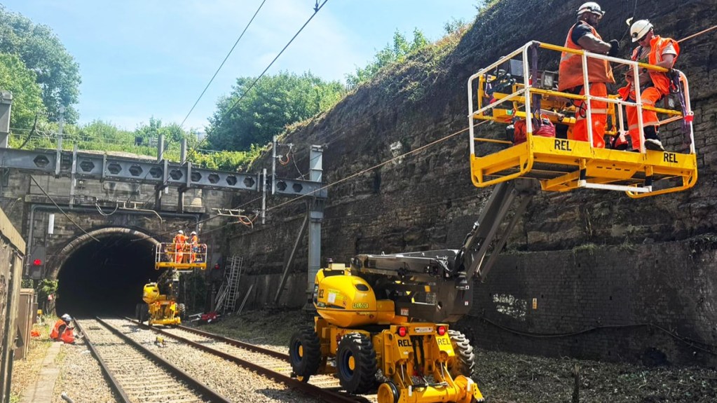 Two rail-mounted elevated work platforms, each carrying two engineers in raised buckets, positioned at the entrance to the Severn Tunnel during overhead wiring upgrade works.