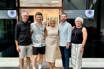Five members of the Stephen Evans Optometrists team smiling outside their Kings Road practice in Swansea's SA1 Waterfront (left to right): Stephen Evans, Henry Evans, Caroline Paul, Ben Packer and Chrissy Evans, with the practice's award-winning signage visible in the background.
