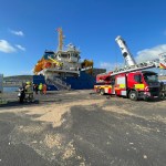 The bow of the JSP Samsø, a blue-hulled multi-purpose cargo ship registered in Madeira, moored at King's Dock in Swansea on a clear blue sky day