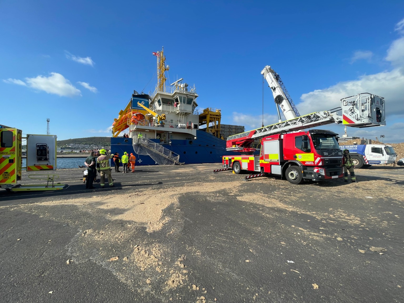 The bow of the JSP Samsø, a blue-hulled multi-purpose cargo ship registered in Madeira, moored at King's Dock in Swansea on a clear blue sky day