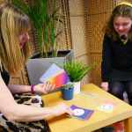 A young woman in school uniform sits in conversation with a smiling adult counsellor, both engaged in a one-to-one wellbeing session as part of The Exchange programme