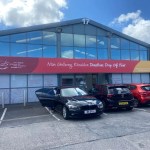 Exterior of the Wales Air Ambulance Charity donations drop-off point at Unit 17 Cwmdu Industrial Estate, with bilingual Welsh and English signage above the entrance and several cars parked outside