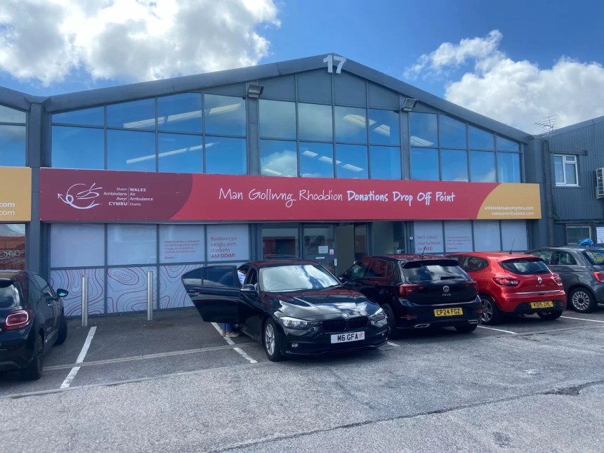 Exterior of the Wales Air Ambulance Charity donations drop-off point at Unit 17 Cwmdu Industrial Estate, with bilingual Welsh and English signage above the entrance and several cars parked outside