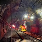 Engineers working inside the Severn Tunnel on the overhead electric wiring system, with the tunnel walls visible in the background.