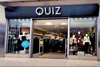 The exterior of the Quiz Clothing store inside Swansea’s Quadrant Shopping Centre, showing the Quiz fascia above the shopfront with mannequins in the window display and a 30% off sale sign visible