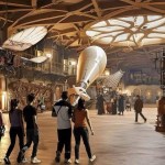 An artist’s impression of a large indoor gallery space with a high vaulted ceiling, featuring hanging vintage aircraft, a large rocket, ornate wooden carvings and groups of visitors exploring the exhibits
