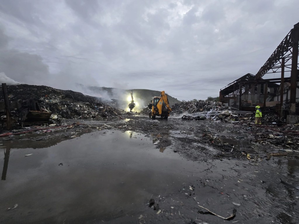 JCB crews assist firefighters working through the debris at the Water Street site. Image: MWWFRS