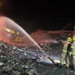 Night shot, two firefighters with hose. Caption: Mid and West Wales Fire and Rescue Service crews work through the night at the Water Street industrial fire in Port Talbot. Image: MWWFRS