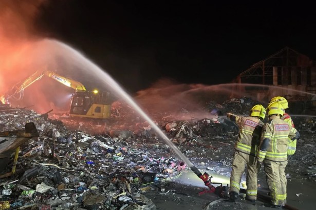 Night shot, two firefighters with hose. Caption: Mid and West Wales Fire and Rescue Service crews work through the night at the Water Street industrial fire in Port Talbot. Image: MWWFRS