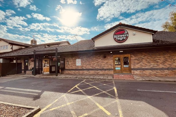 The rear entrance of the Sandpiper Brewers Fayre pub restaurant on Sandy Road in Llanelli, showing the Brewers Fayre branded fascia above the entrance, brick exterior and car park in the foreground under a sunny sky