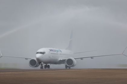 WestJet Boeing 737-8 MAX aircraft passing through a water arch created by airport fire crews as it taxis to the stand at Cardiff Airport.