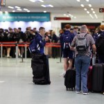 Passengers with luggage queuing at check-in desks inside Cardiff Airport, with a WestJet sign advertising direct flights to Toronto