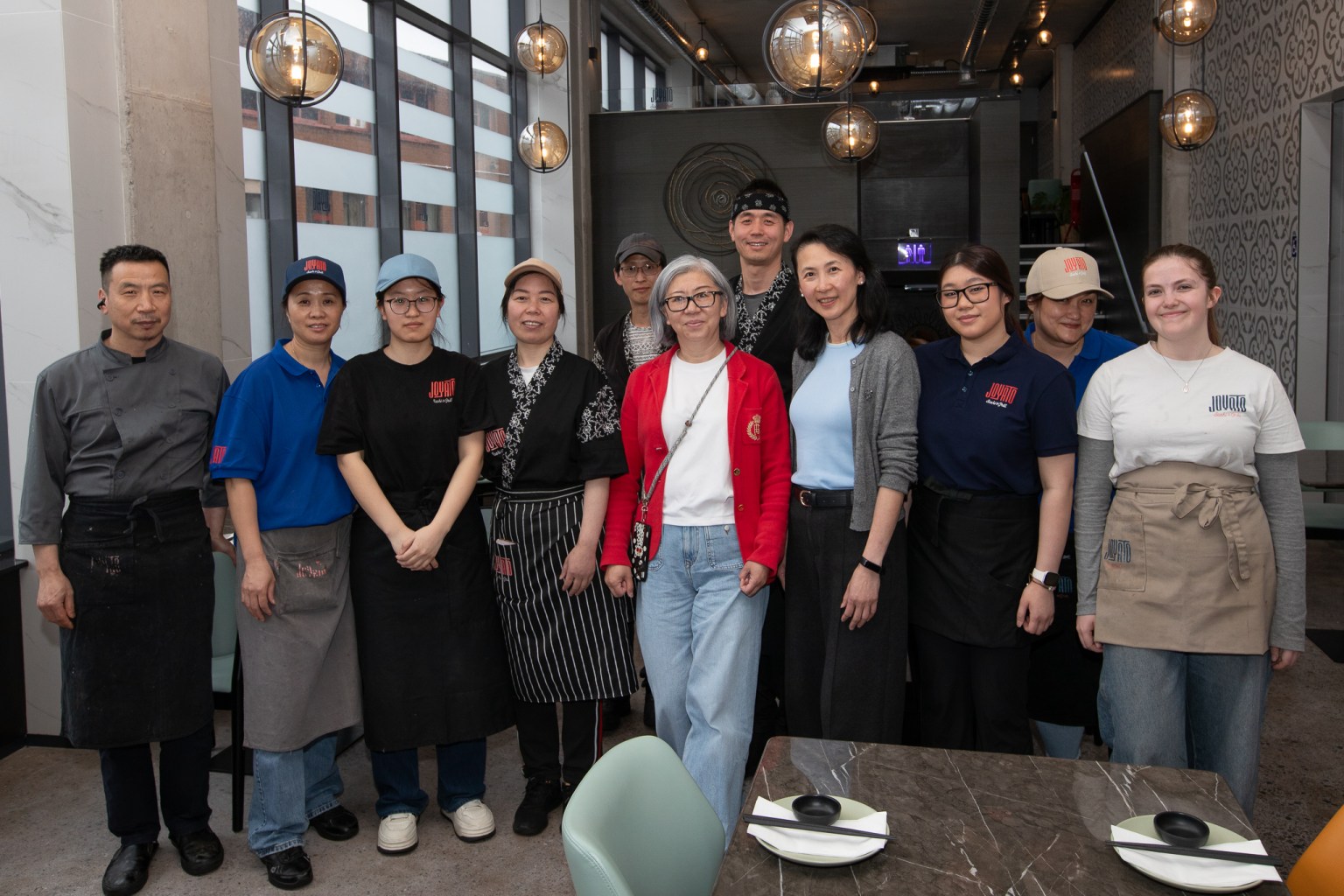 Restaurant staff standing together inside Joyato in Swansea, with director Alice Yi in a red jacket at the centre