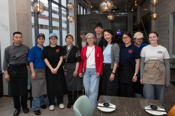 Restaurant staff standing together inside Joyato in Swansea, with director Alice Yi in a red jacket at the centre