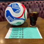 A football, a glass of cola and a sheet of bilingual DES designated driver wristbands on a pub table