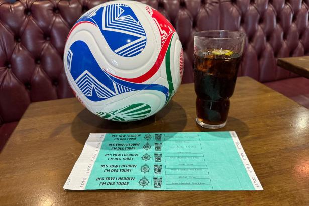 A football, a glass of cola and a sheet of bilingual DES designated driver wristbands on a pub table