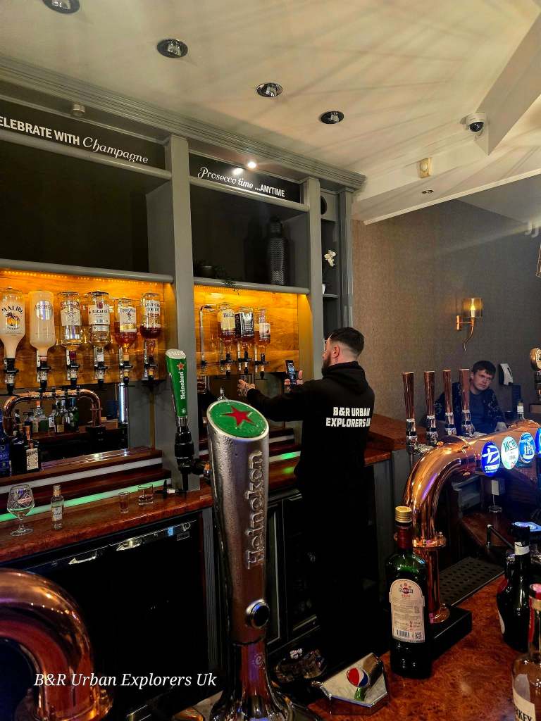A hotel bar with spirit optics, beer taps and bottles still in place, a person photographing it