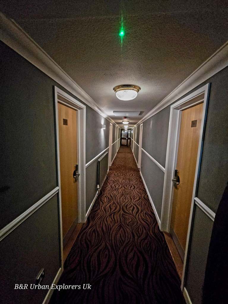 A hotel corridor with ceiling lights on and bedroom doors along both sides