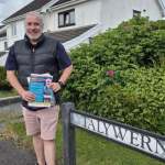 Iwan Griffiths holding Plaid Cymru campaign leaflets beside a Talywern street sign in Llangennech