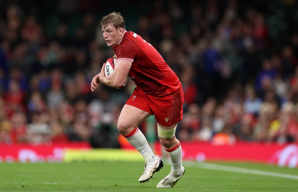 Wales rugby player Jac Morgan running with the ball in a red number 8 shirt during an international.