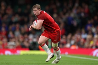 Wales rugby player Jac Morgan running with the ball in a red number 8 shirt during an international.