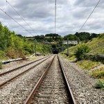 Railway tracks leading towards the mouth of Chipping Sodbury tunnel, with overhead lines and green embankments either side.