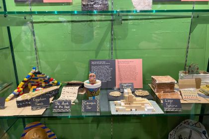 A museum display case showing primary school pupils' ancient Egypt projects — a Lego sphinx and pyramid, a decorated canopic jar, a cardboard sarcophagus and handmade amulets — beside a Terrace Road Primary School information panel.