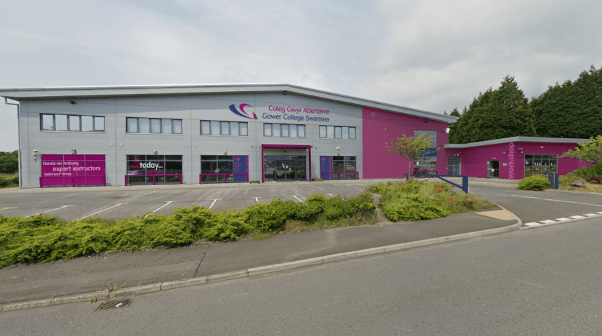A visualisation of a large industrial building rebranded in Gower College Swansea's grey and magenta livery, with college signage and a workshop entrance