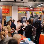 Graduates and employers talking at exhibitor stands during a GradCon careers fair, with banners and information stalls