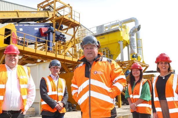 Five people in hi-vis and hard hats stand in front of new yellow recycling sorting machinery at the Griffiths plant.