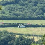 A single-decker bus on its side in a field beside the A484 near Kidwelly, with emergency vehicles including a fire engine on the road behind.