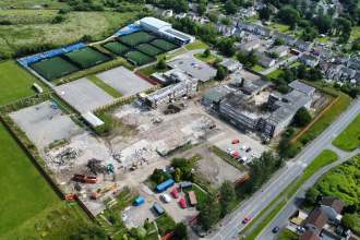 Drone view of the partly demolished former Daniel James school in Mynydd-bach, Swansea, with rubble, diggers and surrounding housing.