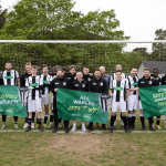 Warley FC players pose in front of a goal holding banners celebrating their rise from the league’s worst team to a fourth‑place finish.