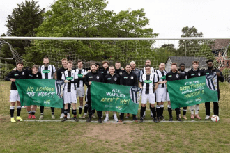 Warley FC players pose in front of a goal holding banners celebrating their rise from the league’s worst team to a fourth‑place finish.