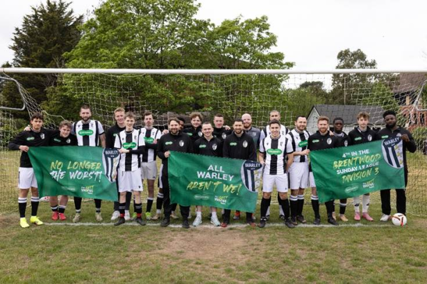 Warley FC players pose in front of a goal holding banners celebrating their rise from the league’s worst team to a fourth‑place finish.