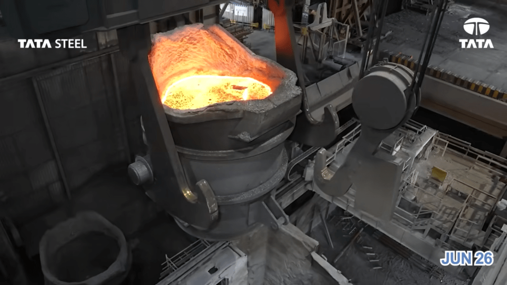 A ladle of glowing molten metal being handled inside the steelworks.