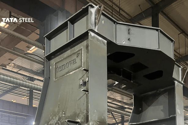 A large grey steel furnace component bearing the Tenova logo, inside a fabrication hall