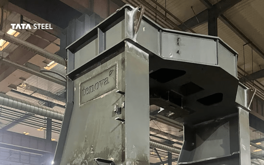 A large grey steel furnace component bearing the Tenova logo, inside a fabrication hall