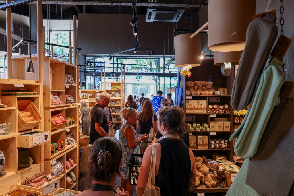 Customers browsing wooden shelves of soft toys, baskets and homewares inside the busy store.