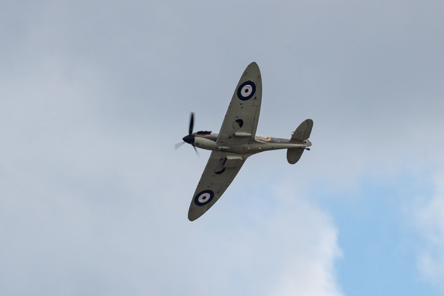 A Supermarine Spitfire of the Battle of Britain Memorial Flight banking against a cloudy sky, RAF roundels visible on its wings.