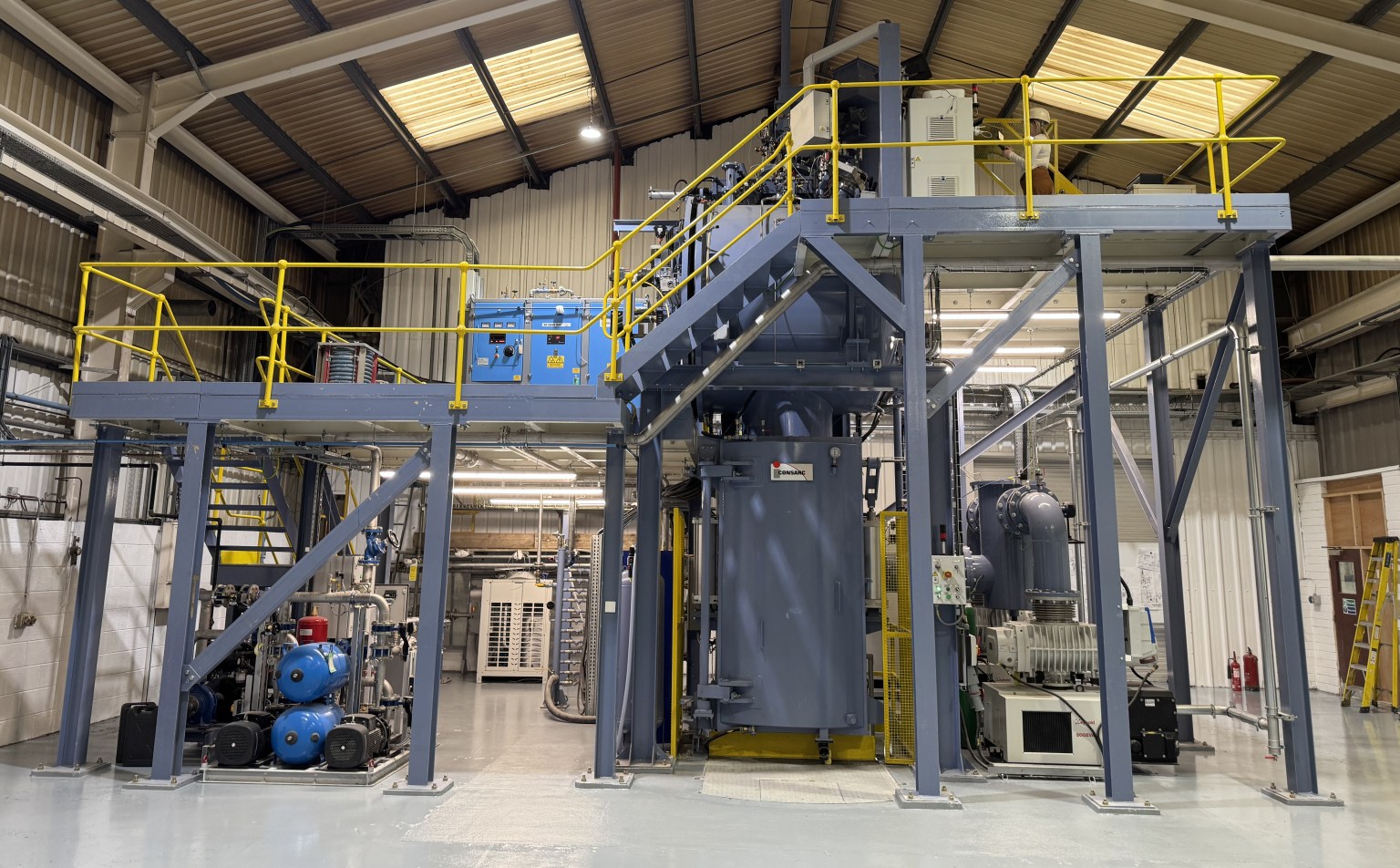Large grey industrial casting furnace and steel gantry inside the Wall Colmonoy plant in Pontardawe.