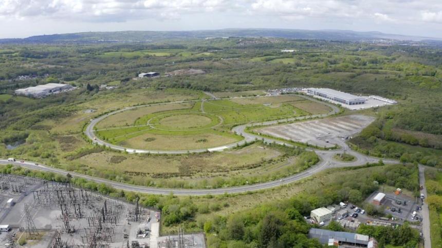 Aerial view of Parc Felindre business park near Swansea, with looping internal roads, empty green plots, an electricity substation and a single large distribution centre.