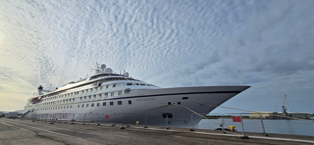 A white cruise ship named Star Legend moored at a quayside under a mackerel sky.