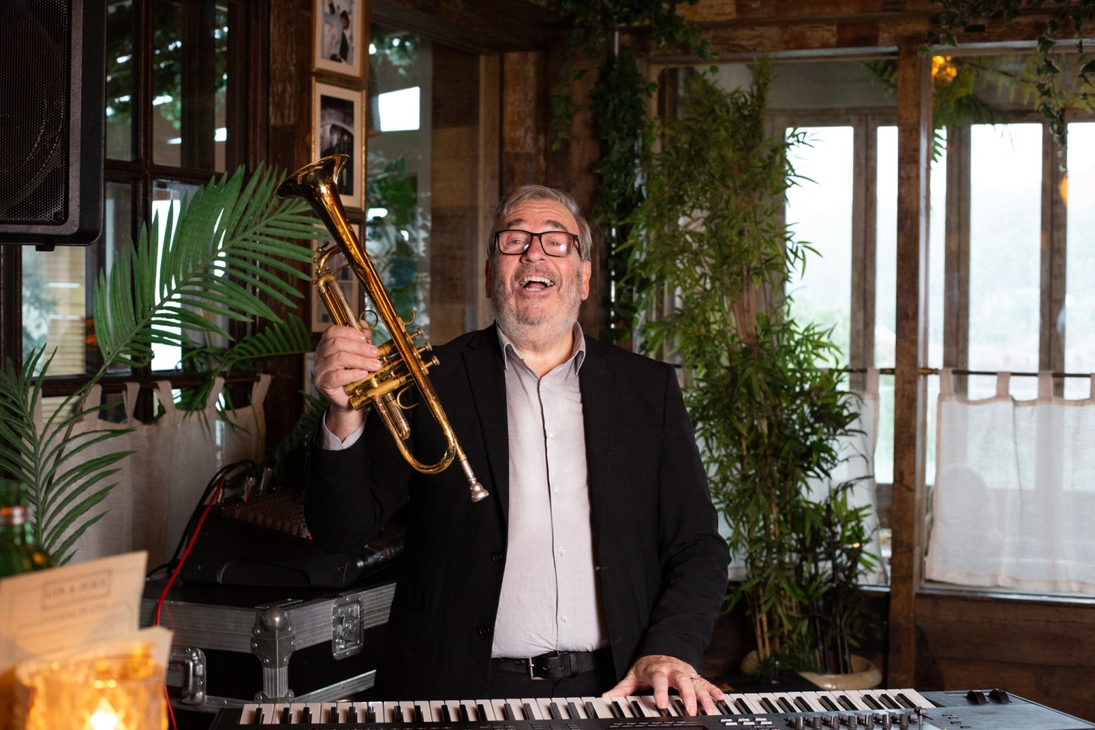 Dave Cottle smiling at a keyboard, holding his trumpet aloft