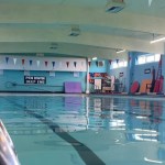 Inside Newcastle Emlyn's community swimming pool, with red, white and blue bunting and a bilingual 'Pen Dwfn / Deep End' sign.