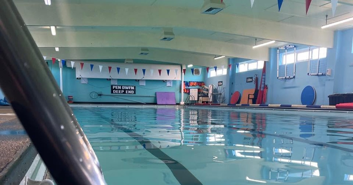 Inside Newcastle Emlyn's community swimming pool, with red, white and blue bunting and a bilingual 'Pen Dwfn / Deep End' sign.