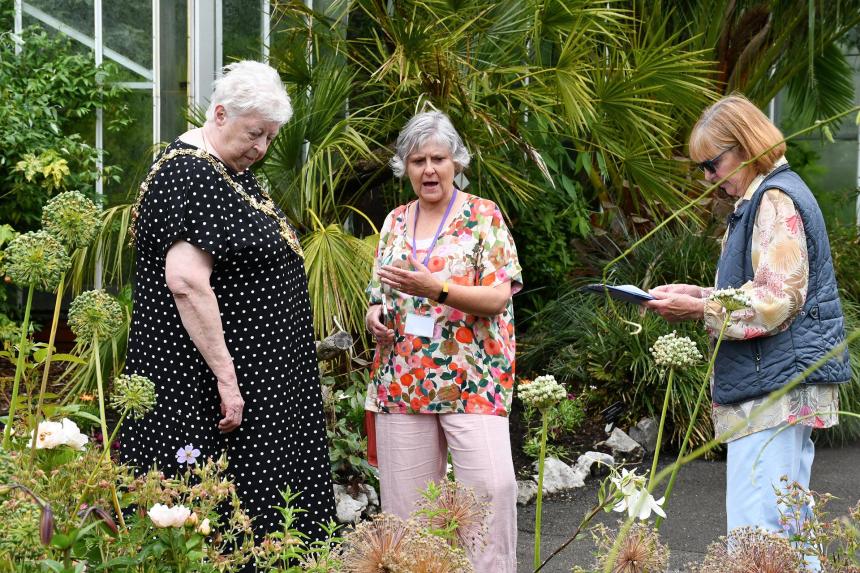 The Lord Mayor of Swansea, wearing her chain of office, looks at planting in the Botanical Gardens with two other women.