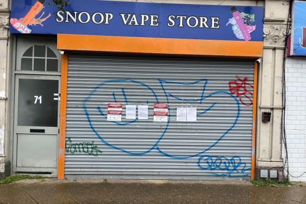 The closed orange-and-blue shutter of Snoop Vape Store on High Street, Swansea, with official Trading Standards closure notices taped to it.